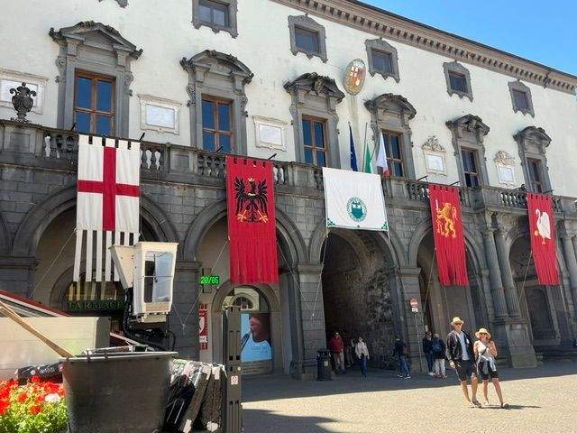 Tourists in Orvieto square with flags draped on an old building