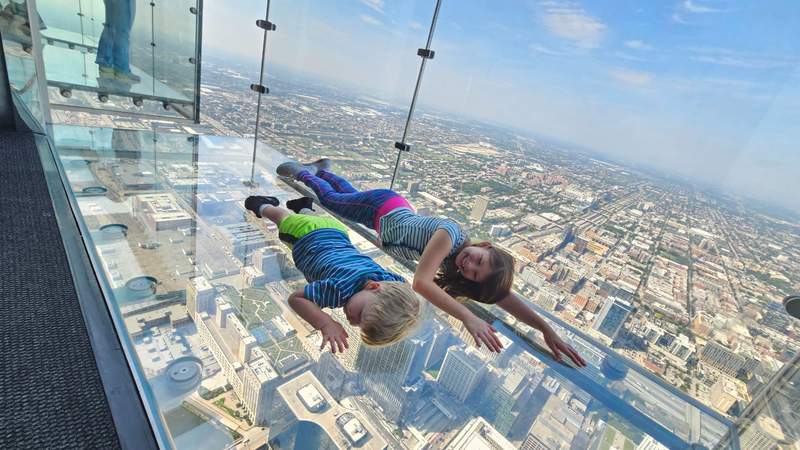 Two kids laying down on the glass of the Skydeck 