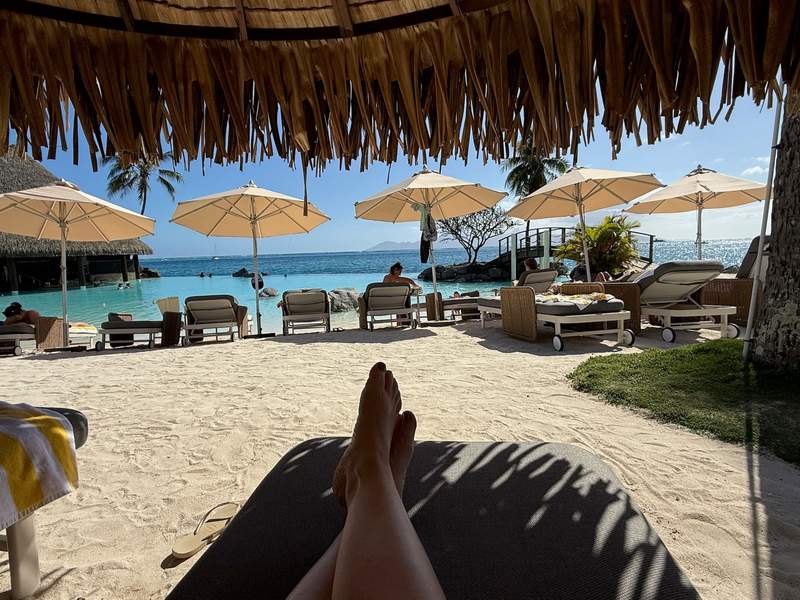 Author’s feet on a reclining beach chair looking towards the pool.