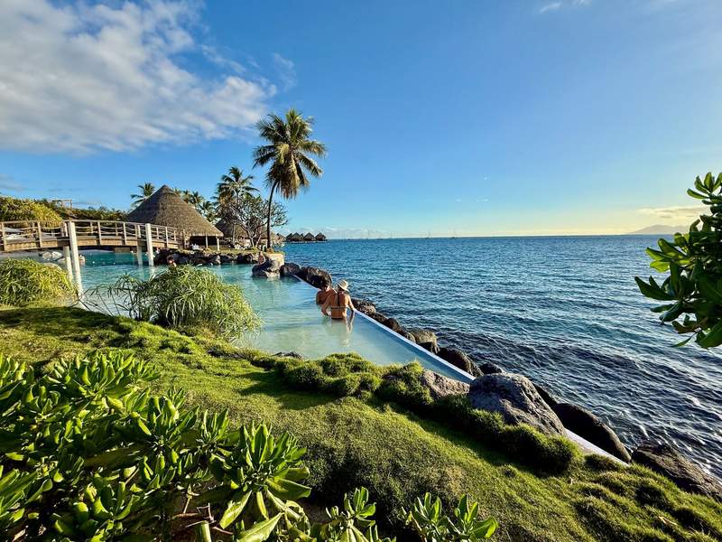 Hotel guests relax in the pool by the beach with the InterContinental Resort & Spa in the background. 