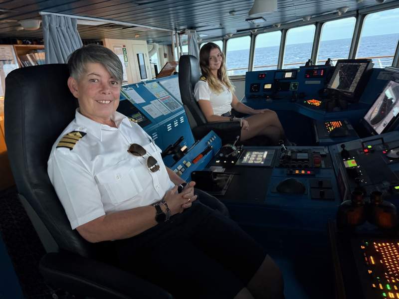 Two female officers sitting at the helm of a ship.