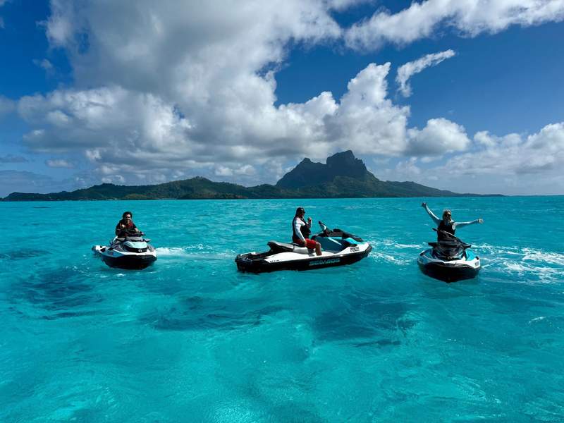 A family each on their own jet ski in turquoise waters.