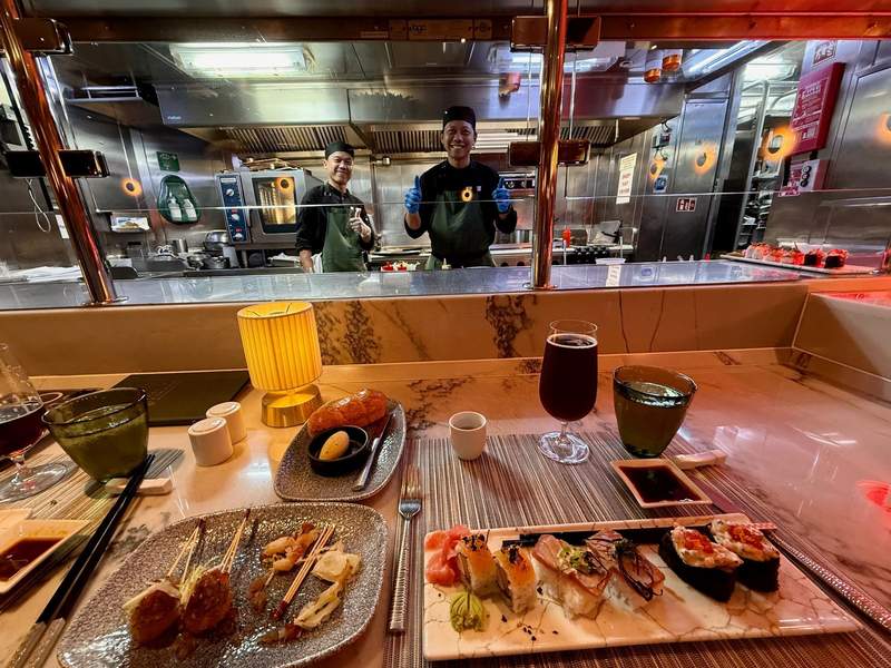 Sushi and other food on a table in front of the happy chefs.