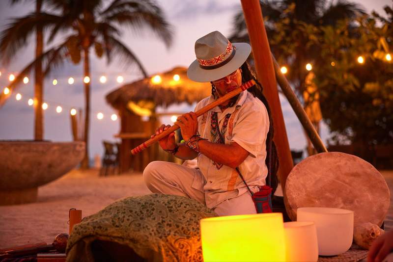 Musician playing a flute during a beachfront cacao ceremony at W Punta de Mita in Mexico.