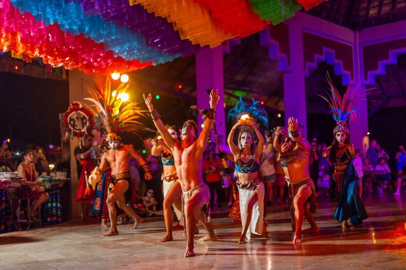 Catrina performers in colorful face paint celebrate Dia de los Muertos at Sandos Caracol in Mexico.