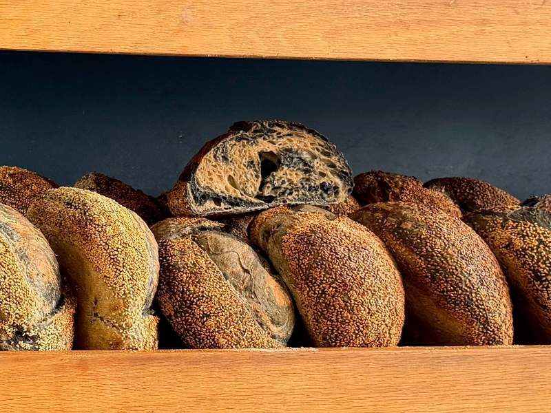 Wooden bakery shelves filled with rustic loaves and seeded breads at Oat Bakery, located next door to Hotel Virginia in downtown Santa Barbara.