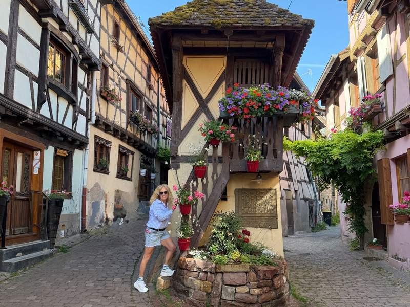 Woman climbing a staircase to a very small apartment in tudor style decorated with colorful flowers.