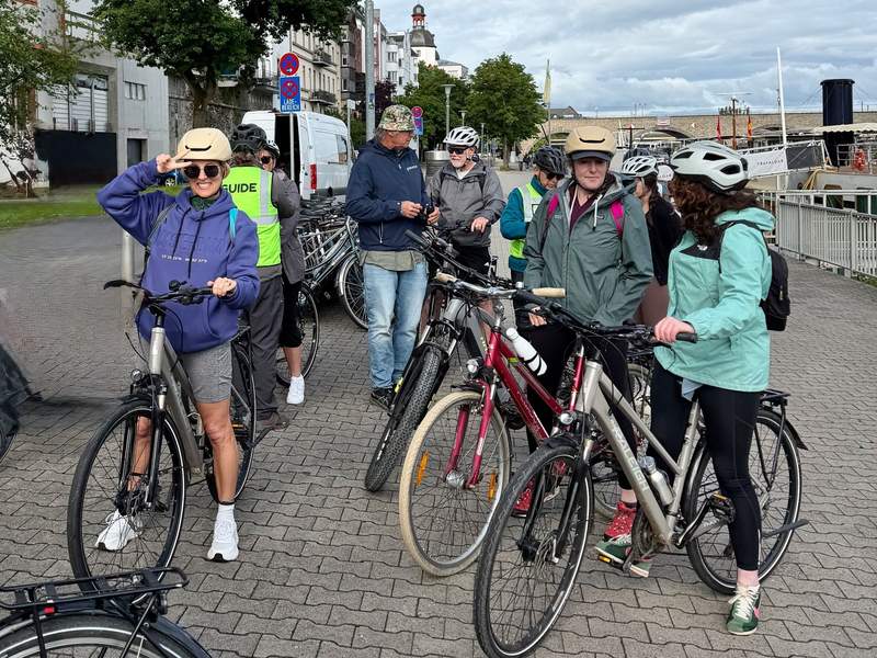 Several people on bikes wearing helmets paused for a rest on the bricked bike trail.
