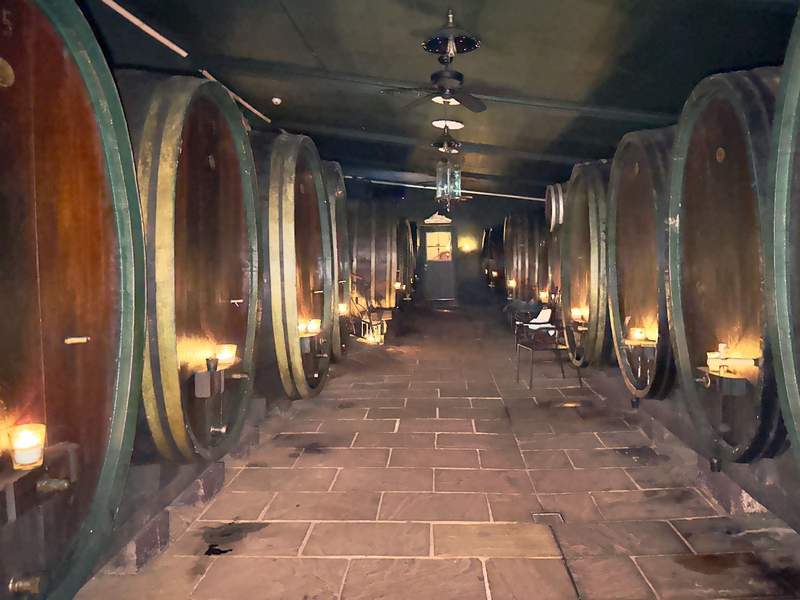 6 large vinegar barrels lit by candlelight in a cellar