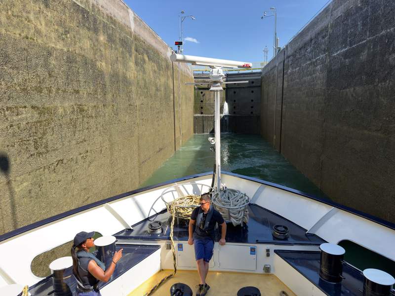 Two crew members navigate the ship through the locks, waiting for the lock to fill with water.