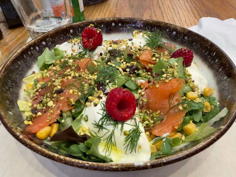 Large salad topped with smoked salmon, raspberries, chopped pistachios, fresh dill and creamy cheese served at Hilton Milan.