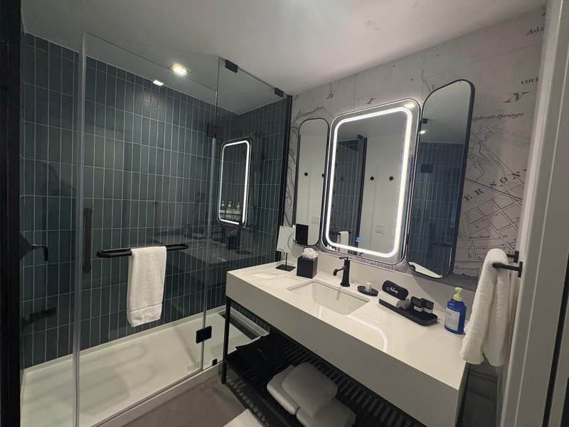 bathroom vanity with lighted mirrors against a vintage map wall