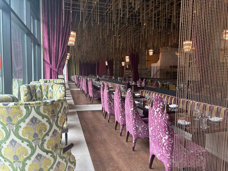 A photo of the dining room of Steakhouse Bourré Bonne with purple patterned chairs and elegant hanging ceiling displays.