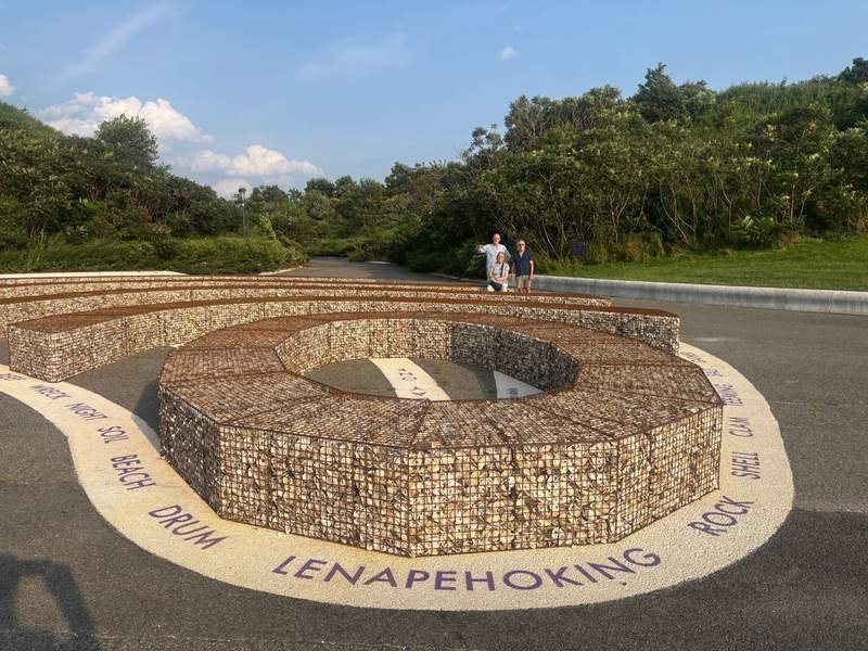A large gabion-style stone sculpture shaped in a spiral on an outdoor path