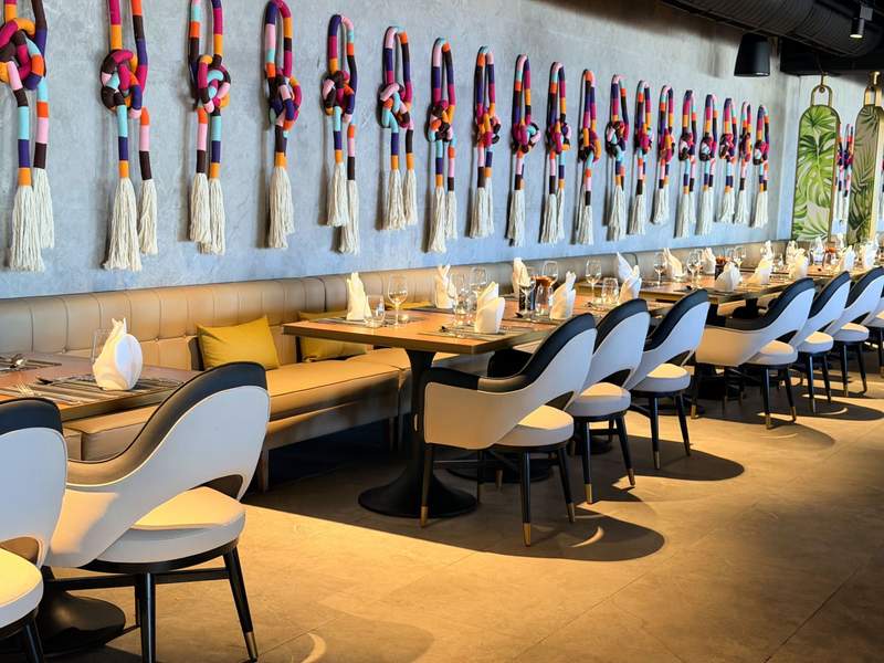 Stylish resort restaurant with colorful rope-inspired wall décor, upholstered seating, and neatly arranged dining tables at Princess Grand Jamaica.