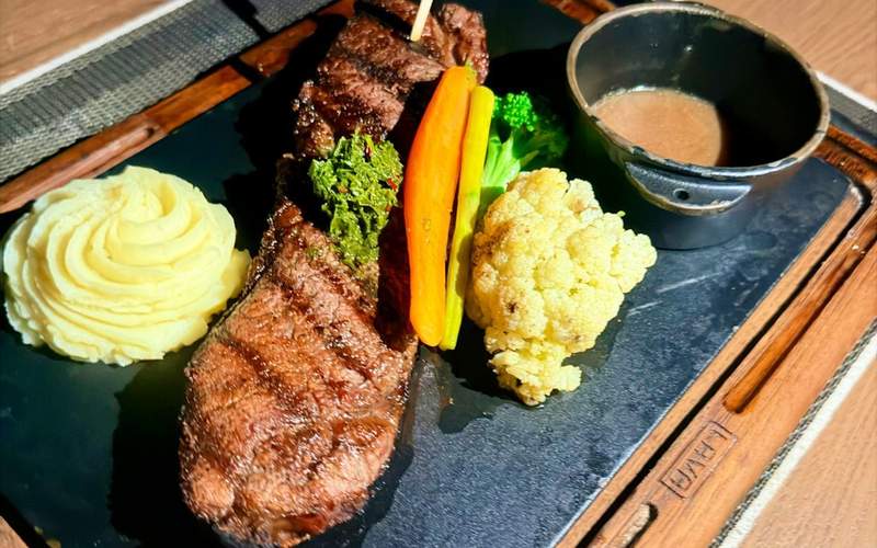 Grilled steak with mashed potatoes, roasted vegetables and sauce.