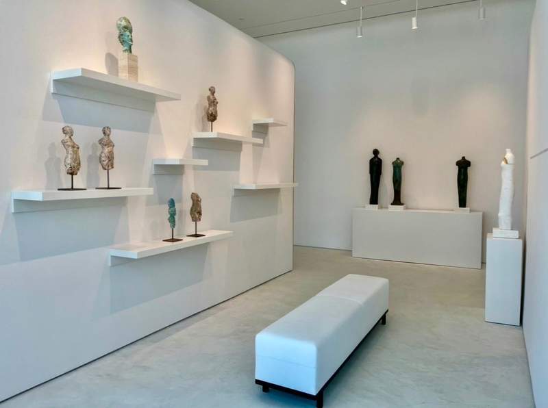 An art gallery with white walls and displays of sculptures