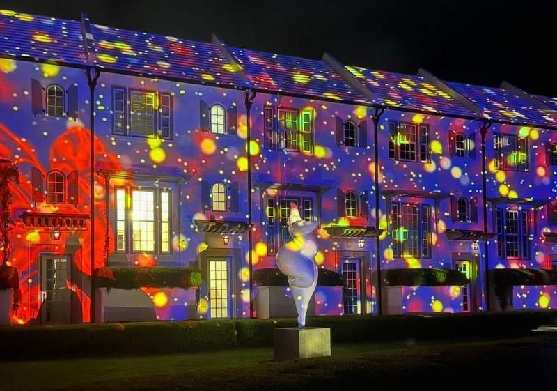 A building lit up at night by a colorful digital art projection in Alys Beach