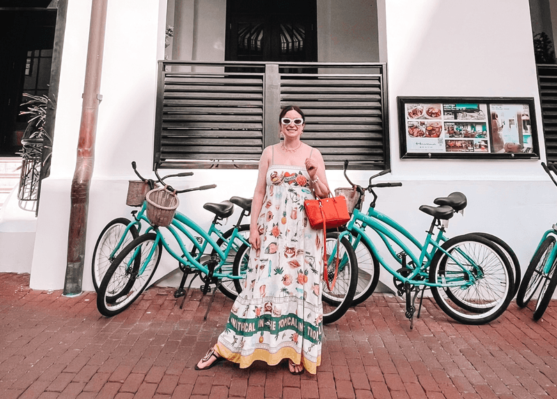 A woman standing in front of a group of turquoise beach cruiser bicycles