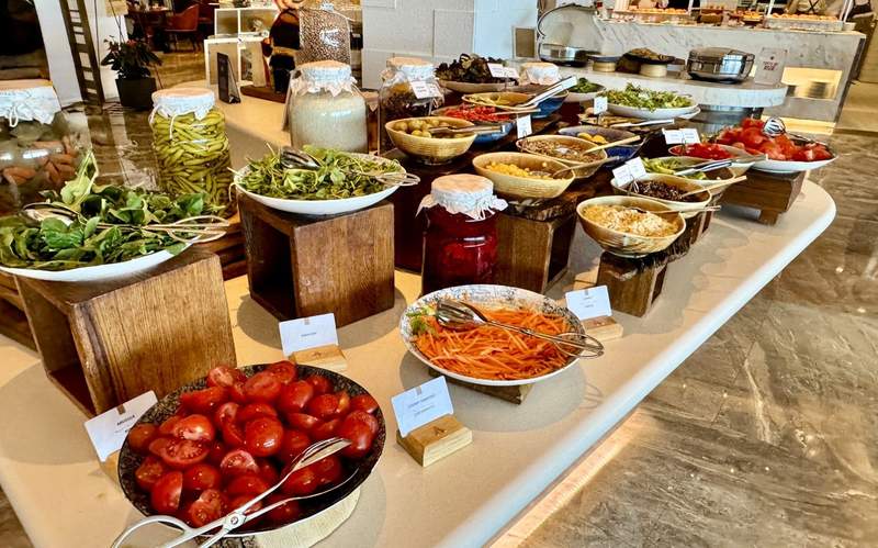 Breakfast buffet at Conrad Istanbul Bosphorus featuring fresh tomatoes, greens, vegetables, grains, pickled items and other Turkish breakfast selections