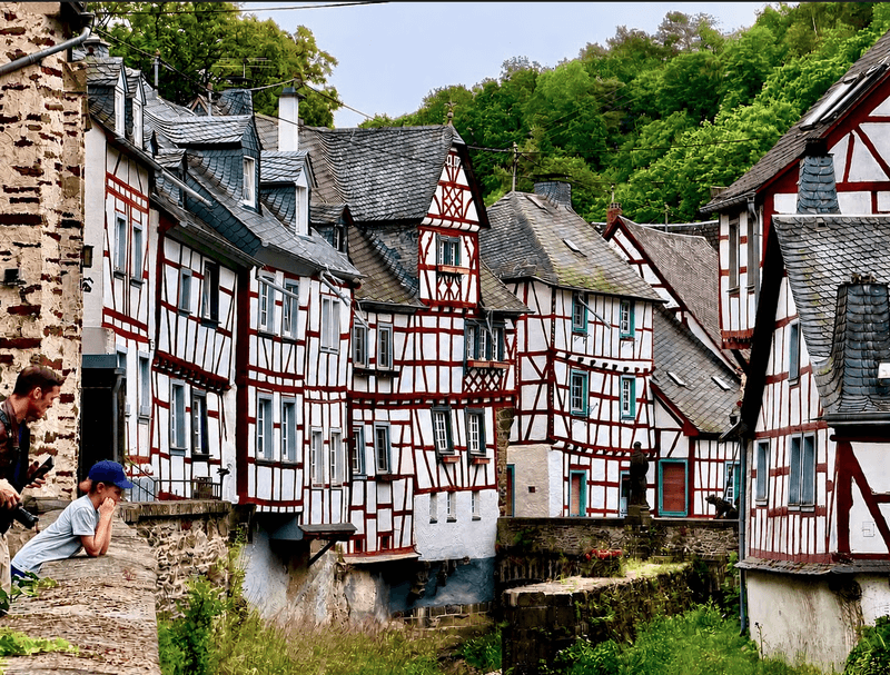 Father and son admire the traditional red-and-white half-timbered houses lining a picturesque street in Monreal Germany