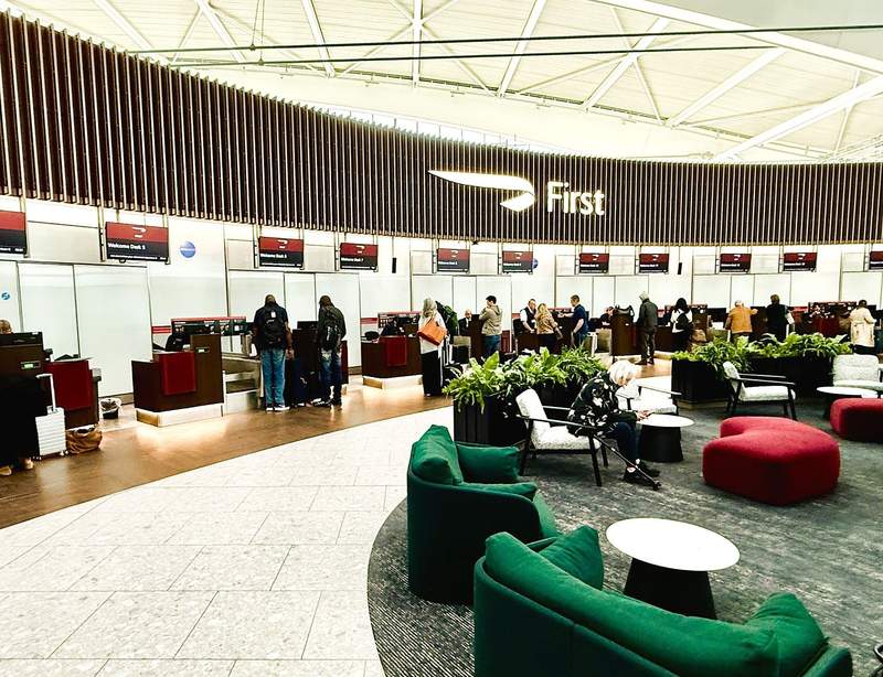 British Airways First Class check-in area at London Heathrow Airport, with dedicated service desks and a comfortable seating area for premium passengers