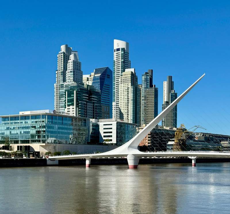Aires city skyline and waterfront with the striking white Puente de la Mujer bridge in Puerto Madero under a clear blue sky