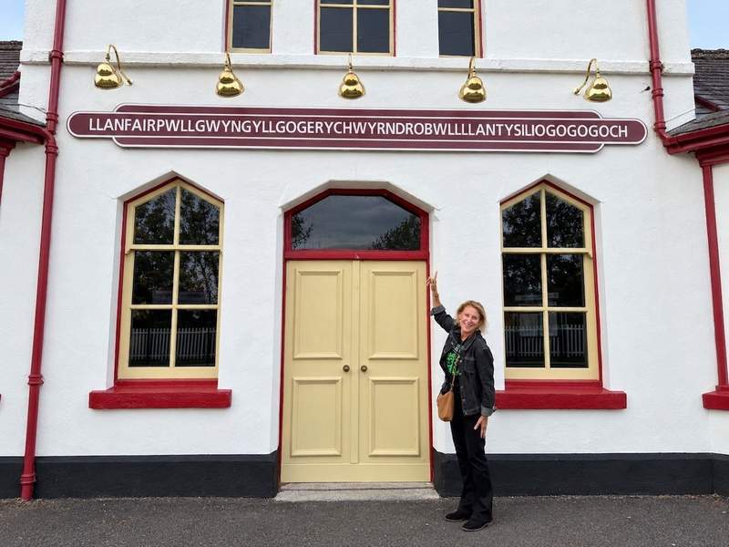 Sharon Kurtz beneath the Llanfairpwll railway station sign on Anglesey
