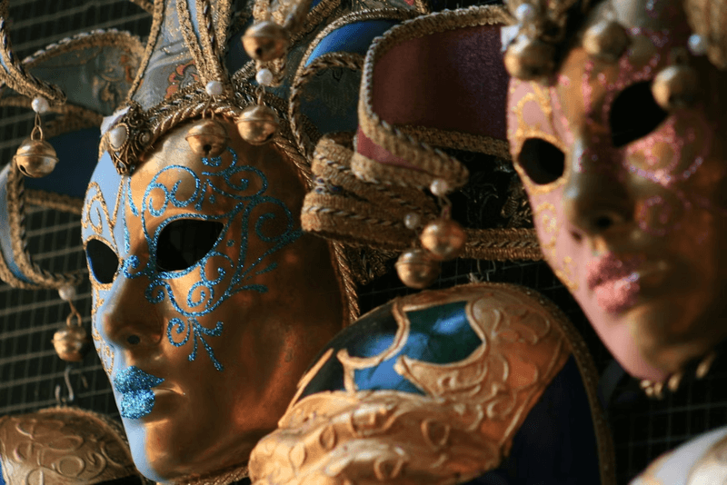 Close-up of a display of gold and colored Venetian carnival masks. 