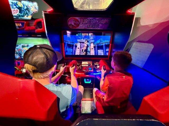Two boys playing Jurassic Park arcade game.