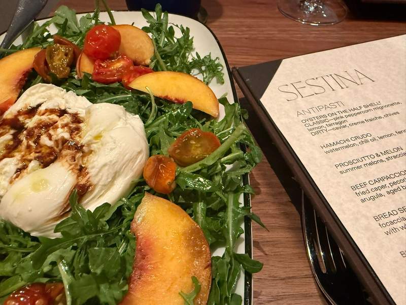 The menu at Sestina at The Compton in Bentonville featuring a burrata salad with local peaches.