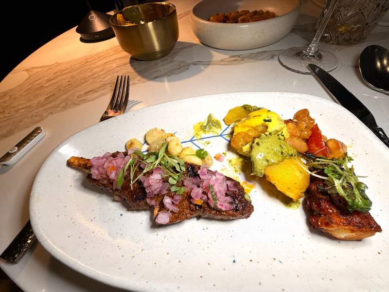 A plate filled with Peruvian food including meats, beans, and potatoes.