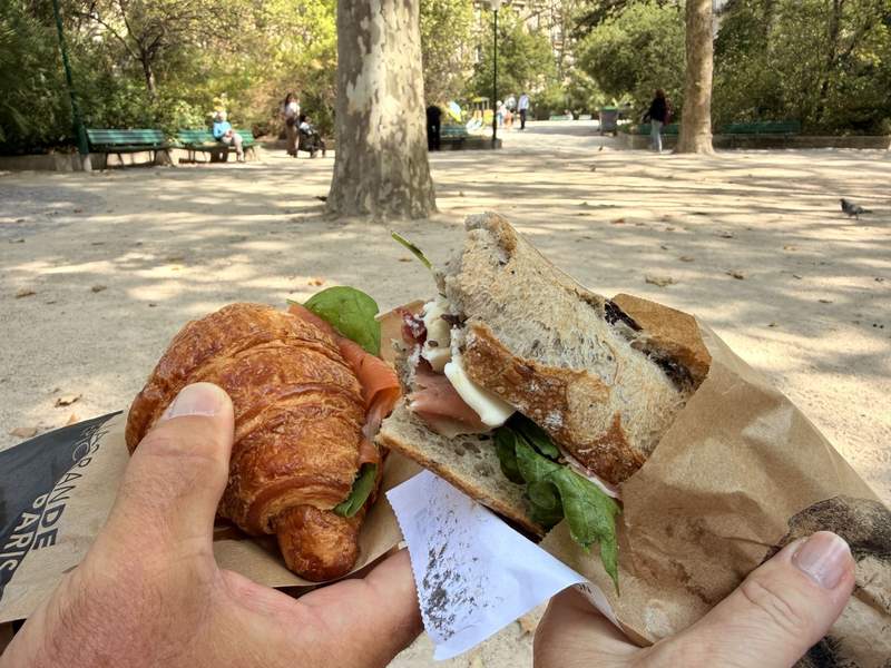 A couple toasting with sandwiches in a Paris park