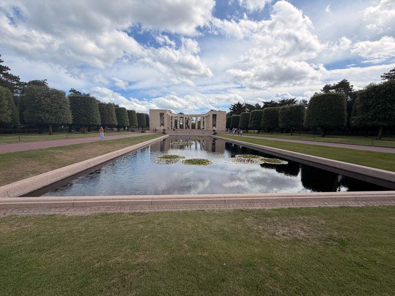 Reflecting pool with a columned memorial in the background surrounded by trees.