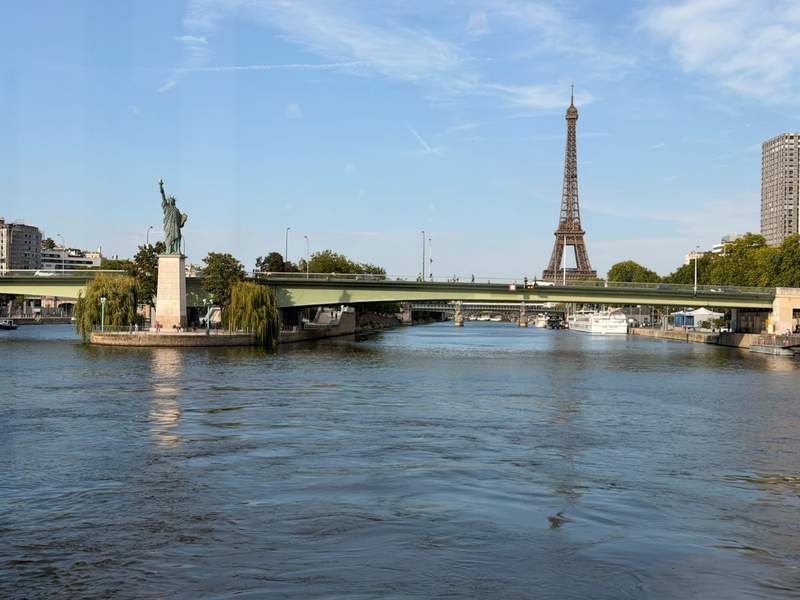 Small Statue of Liberty to the left, a bridge and the Eiffel Tower in the background.