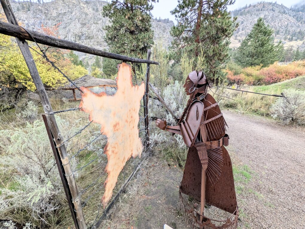 A metal sculpture of a First Nation man stretching a bear skin