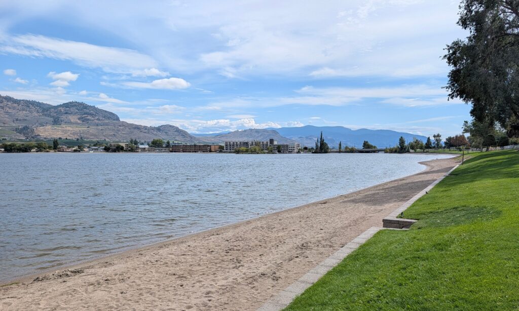 the beach along Lake Osoyoos with the mountains in the background