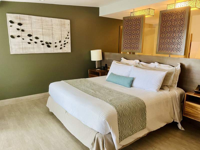 A king-sized bed in a neutral colored hotel room