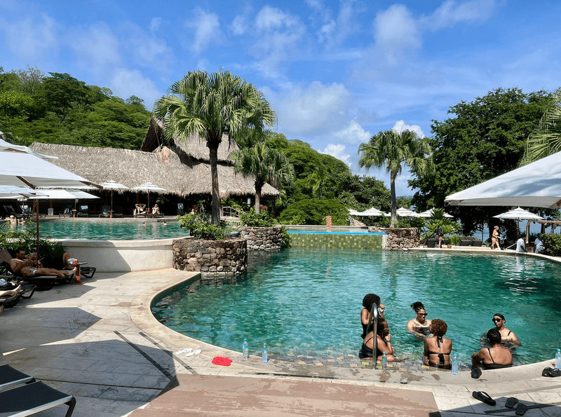 A resort pool with a group of friends hanging out inside.