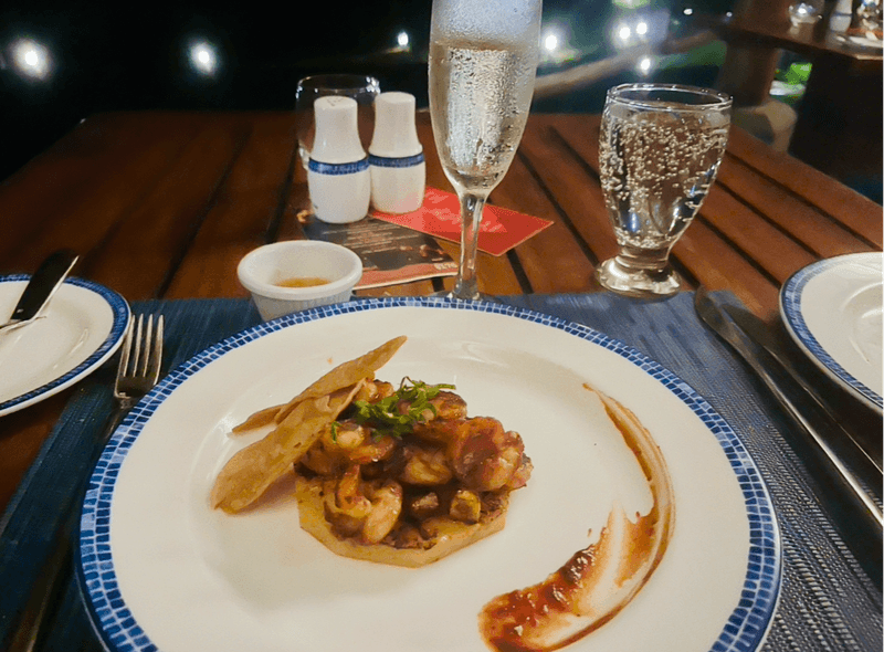 grilled shrimp on a plate with a glass of sparkling wine