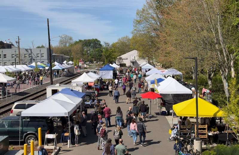 Shoppers walking among vendor tents at the Albany Farmers’ Market in Albany Oregon