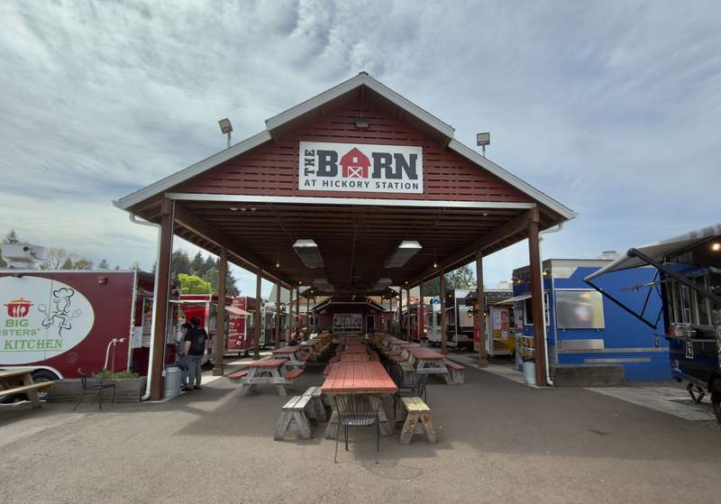 Covered seating area surrounded by food trucks at The Barn at Hickory Station in Albany Oregon