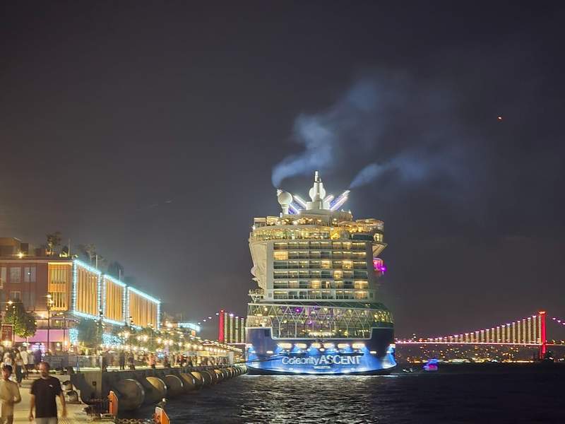 Celebrity Ascent docked at night with illuminated bridge in the background