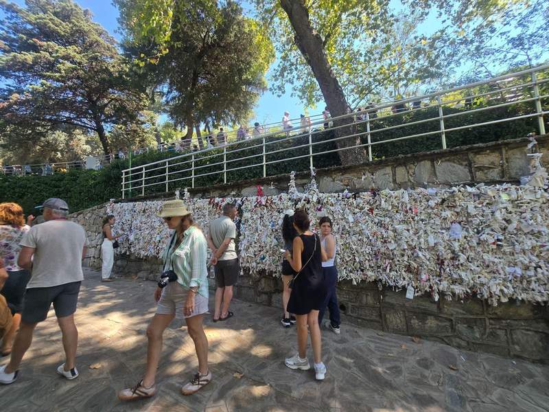 Visitors at a wall covered with paper notes in Ephesus