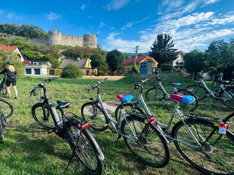 Touring bikes parked below stone castle ruins during a cycling stop along the Danube.