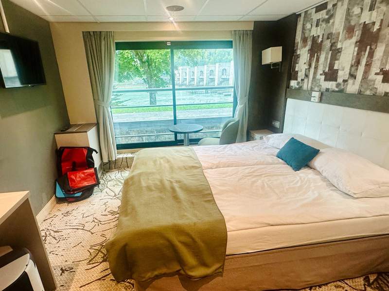 Cabin aboard the MS Lisabelle with a double bed, small sitting area and floor-to-ceiling sliding glass door.