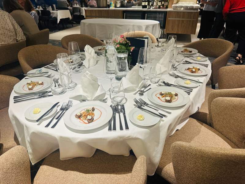 Dining table set for dinner aboard the MS Lisabelle with plated appetizers, white linens and glassware.