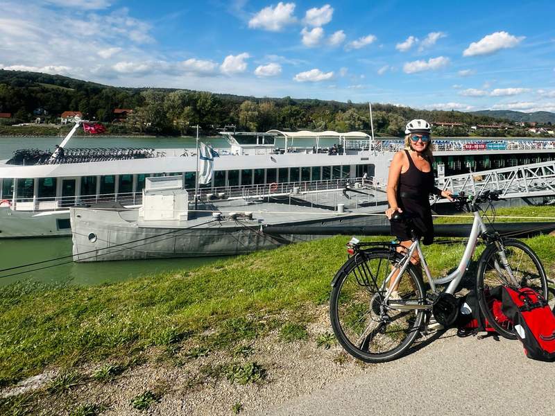 A cyclist wearing a helmet stands with an e-bike beside the MS Lisabelle on the Danube.