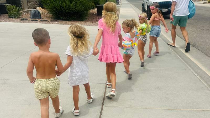 Six grandchildren in swimsuits and cover-ups walk together toward the pool during a family vacation in St. George, Utah.