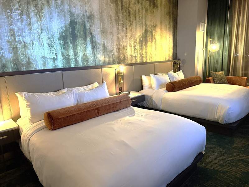 Deluxe double queen hotel room with white linens and bolster pillows at Wind Creek Chicago Southland.